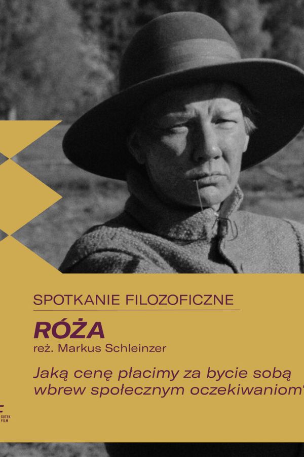 Czarno-biały plakat promocyjny filmu „Róża”, przedstawiający osobę w kapeluszu oraz tekst w języku polskim dotyczący spotkania o charakterze filozoficznym.